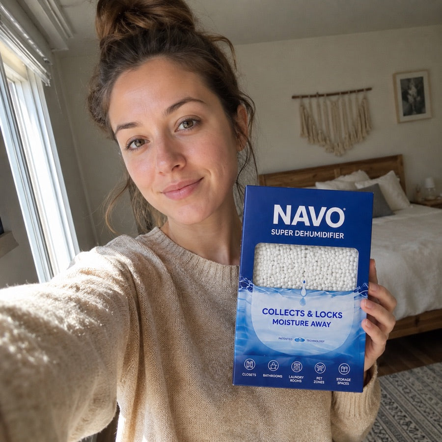 NAVO customer holding a boxed dehumidifier in a bedroom