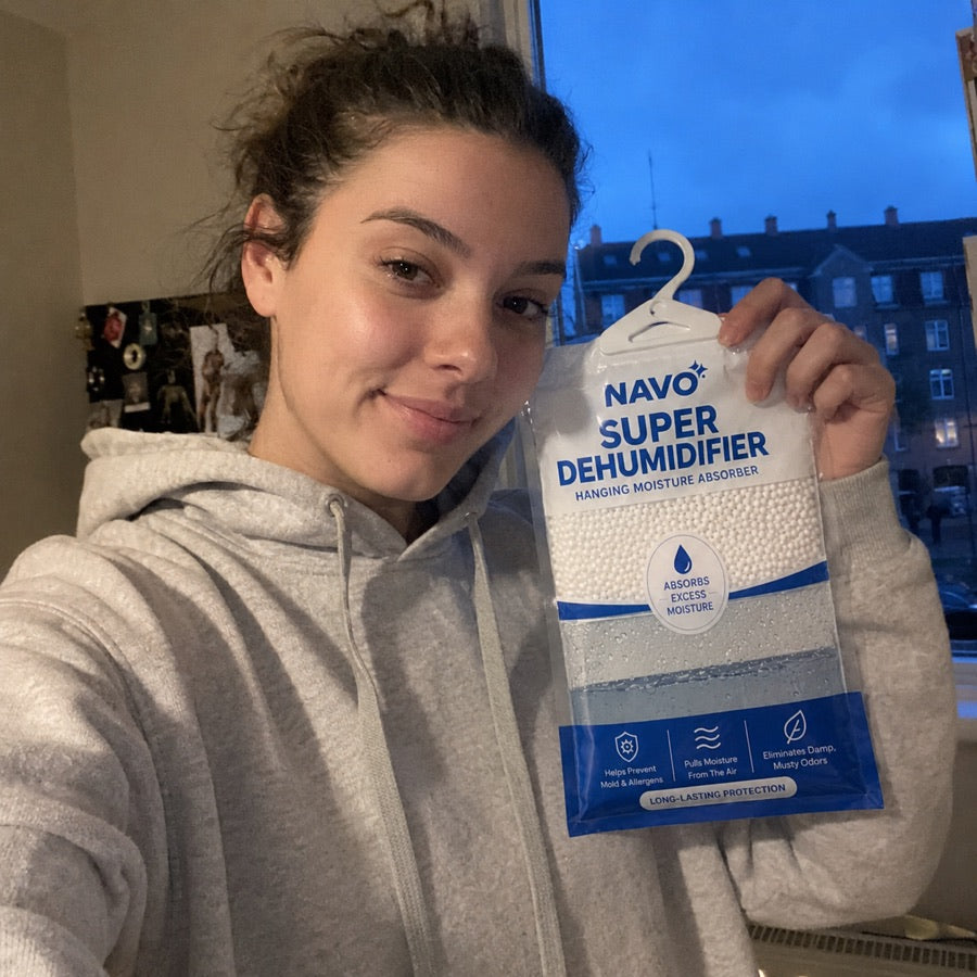 NAVO customer holding a hanging moisture absorber near a window