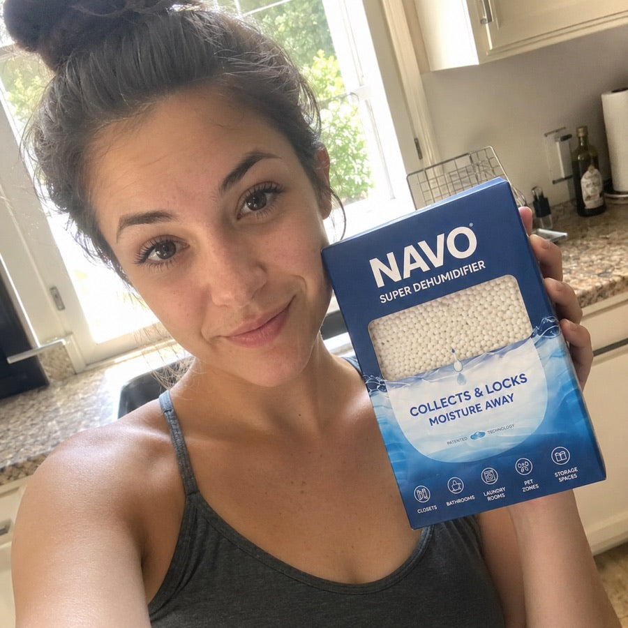 NAVO customer holding a boxed dehumidifier in a kitchen